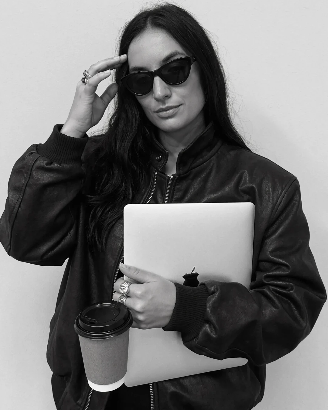Lucía en blanco y negro con gafas de sol, café y portátil